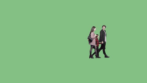A young family with a little boy is walking on a green screen background.