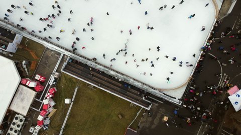 Kiev, Ukraine, January 2, 2022:-Aerial Drone View Flight Over many people skating on open-air ice rink in winter. Urban Ice skating top view. Publik Ice Rink. Winter outdoor. Skating sport background