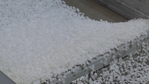 Propylene or polyethylene pellets - white recycled plastic granules on shale shaker of waste plastic recycling machine - close up. Environmental protection, separation, technology concept