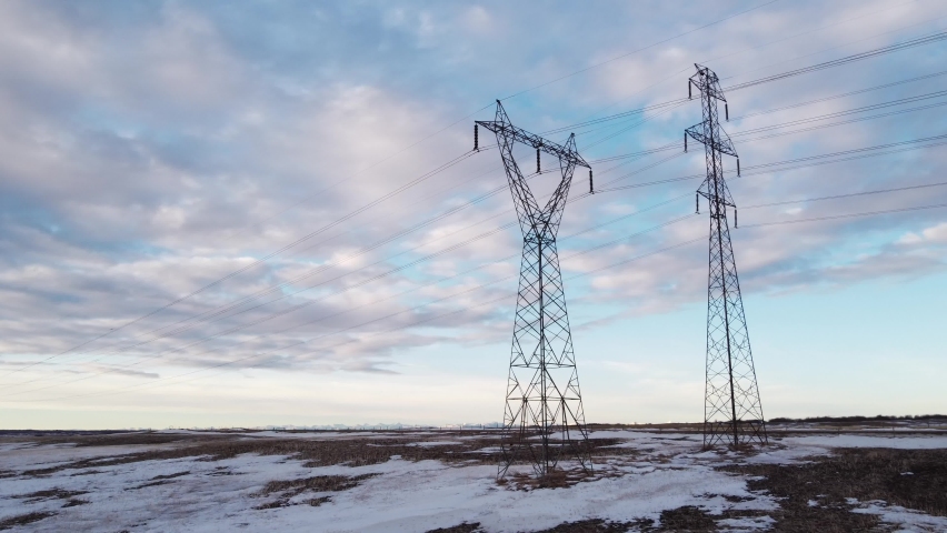 Low Aerial Flight of power lines and transmission transmission towers on the Alberta Prairies during winter. Royalty-Free Stock Footage #1086620405