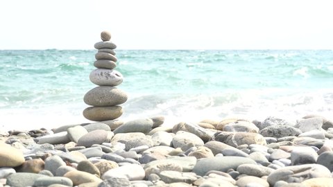 Stone balance closeup. Female hand making pebbles tower from sea stones. Macro of pyramid of pebbles on beach. Stack of stones on seashore. Meditation and relax on summer vacations concept