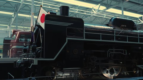Nagoya.Japan-October 31.2019: A steam locomotive with a Japanese flag at the Nagoya railway museum. Vintage transportation technology. Black. Camera slowly turning right.