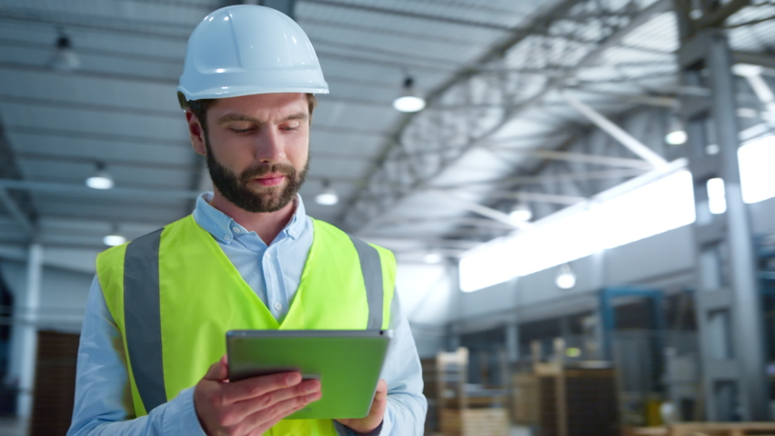 Portrait focused factory employee checking tablet information inspecting storage. Hardworking manufacture specialist worker in helmet analysing production process. Manufacturing occupation concept | Shutterstock HD Video #1086624335