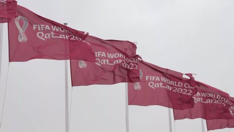 Doha, Qatar - January 15th 2022: Multiple Maroon Fifa World Cup Qatar 2022 flags flying in the sky above Doha
