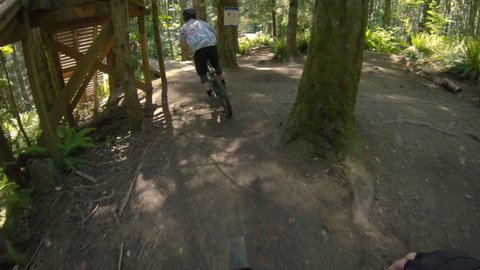 Mountain Bike Park POV Following Friend Off Wood Drop Obstacle. Chest mount angle biking over log jump at Duthie Hill