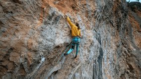 aerial slow motion back view strong man rock climber climbs on overhanging limestone cliff with tufas and colonets. sport and lifestyle outdoors