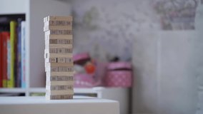 Cute curious little girl accidentally crashes tower of wooden blocks. Concept of board developing games. Slow motion video