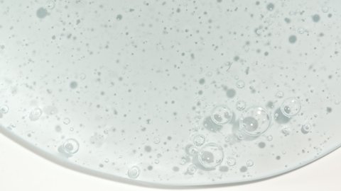 Macro Shot of Transparent Blue Cosmetic Fluid Gel, Cream With Bubbles Flowing down on a White Surface. Natural Organic Cosmetics, Medicine.