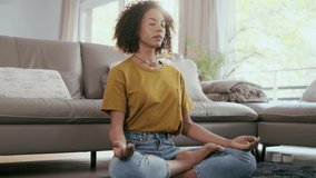 Video of relaxed mature woman in lotus position sitting on the floor in the living room at home.