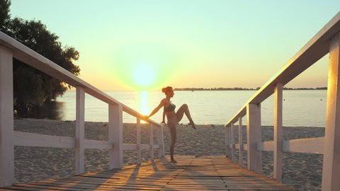 barre. stretching outdoors. yoga beach. ballet workout. Athletic young woman is doing exercises at the beach during sunset or sunrise. Fitness training outdoors. Fitness, ballet, sport, yoga and
