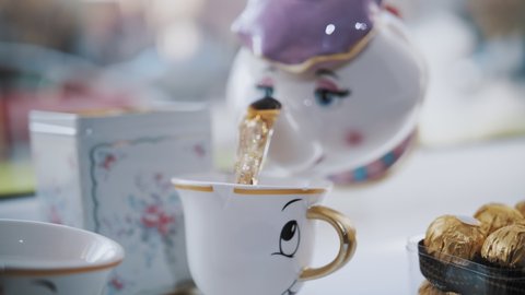 tea party. close-up. funny kids tea set. hot tea is poured into a cup from a teapot.