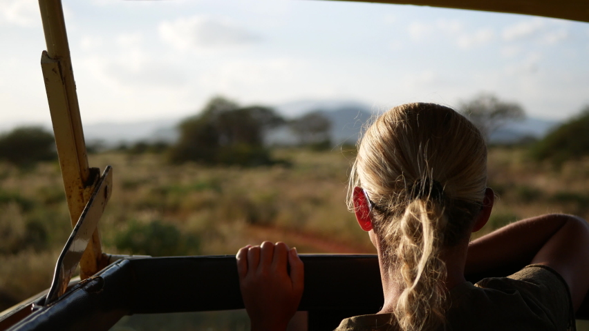 Africa Safari wildlife view Blonde lady Woman girl from a car jeep drive on a safari adventure trip in Masai Mara park Kenya savana tsavo west tanzania Royalty-Free Stock Footage #1086646211