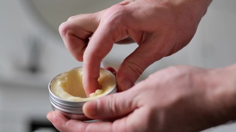 Male hands manipulating a hair styling product from a tin