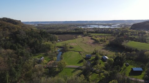 Gorgeous view of valley in Wisconsin with the Mississippi River on a bright sunny day. Agricultural farm with meadows, creek, pond, old mill, and plowed field. 