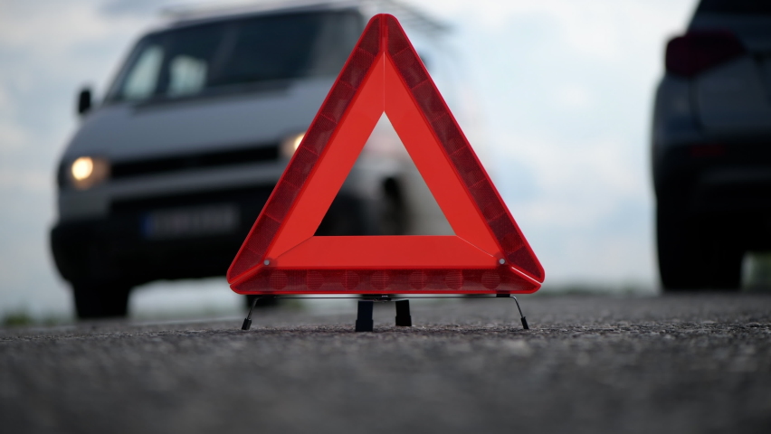 Reflecting warning triangle on the road behind the broken car, another vehicle passing in other direction | Shutterstock HD Video #1086657299
