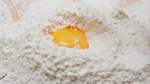 Yolk falls into the flour on a wooden table. Bakery products. Dough preparation.