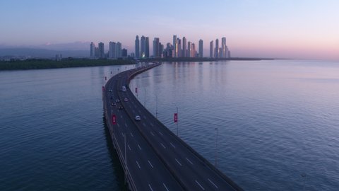 Aerial view of Panama City with car driving down a highway near the ocean, pullback wide shot,