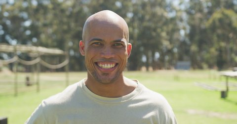Portrait of african american male soldier with shaved head smiling in sun at obstacle course. healthy active lifestyle, cross training outdoors at boot camp.