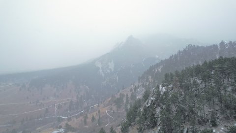 Drone Aerial Footage Flying Over Pine Tree Hillsides in Flatirons Mountain Near Boulder Colorado USA During Snowstorm Blizzard.