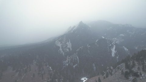 Drone Aerial Footage Near Snowcapped Pine Tree Flatirons Mountain Near Boulder Colorado USA During Foggy Snowstorm Blizzard.