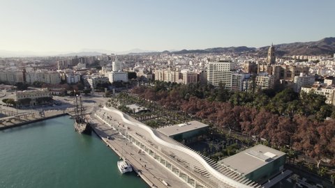 Old wooden ship moored on pier of Paseo del Muelle in Malaga port area and cityscape, Andalucia in Spain. Aerial panoramic view