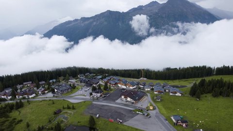 Drone flying towards misty cloudy village in top of mountain summit in Krimml, Austria