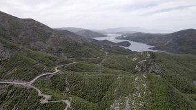 Drone video of frontal plane advancing on the Sh25 in albania with the Drin River in the background as the main plane. You can see some houses and a dirt road with curves and a car driving.