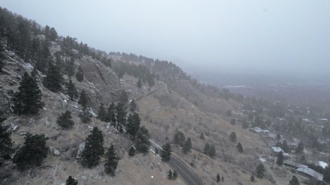 Drone Aerial Footage Flying Over Hillside Country Road in Flatirons Mountain Near Boulder Colorado USA During Snowstorm Blizzard.