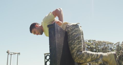 Fit caucasian male soldier on army obstacle course in field climbing over fence and running. healthy active lifestyle, cross training outdoors at boot camp.
