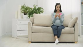 4k video of pregnant woman holding pink and blue papers which mean gender of future baby.
