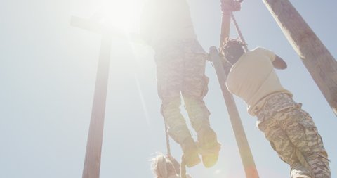 Three diverse fit male and female soldiers climbing ropes on obstacle course. healthy active lifestyle, cross training outdoors at boot camp.