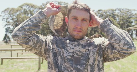 Portrait of caucasian male soldier in combat uniform and cap standing on army obstacle course. healthy active lifestyle, cross training outdoors at boot camp.