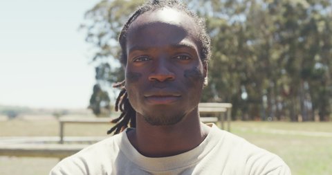 Portrait of confident african american male soldier with dreadlocks and eye black in field. healthy active lifestyle, cross training outdoors at boot camp.
