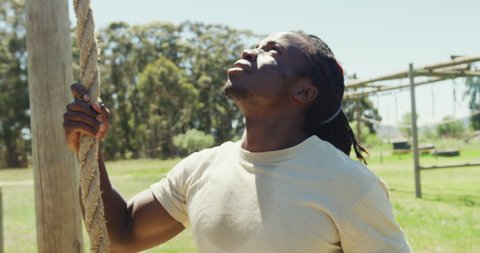 Portrait of african american male soldier with dreadlocks holding rope on army obstacle course. healthy active lifestyle, cross training outdoors at boot camp.