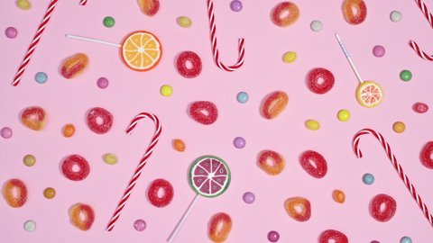 6k Lollypops, candies and gummy candies filling pastel pink background and making pattern. Stop motion animation flat lay
