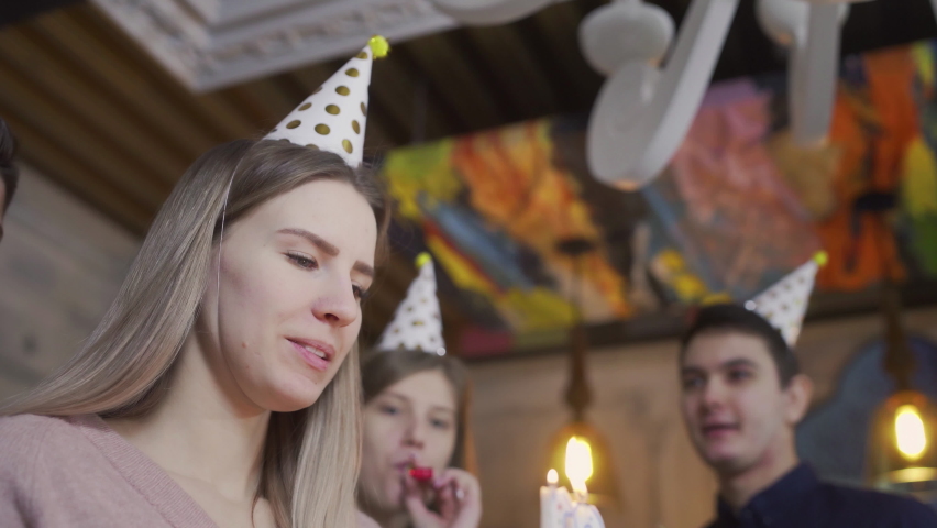 Close-up of a girl blowing out the candles on the cake. Birthday girl delighted with birthday celebration with best friends Royalty-Free Stock Footage #1086668849