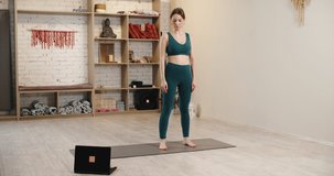 Exercising At A Yoga Studio. Sporty girl doing yoga plank while watching online tutorial on laptop, free space. High quality 4k footage
