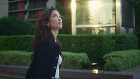 Confident businesswoman walking alone watching city architecture side view. Beautiful woman going down street with green plants in black jacket. Cute asian tourist enjoying modern cityscape outdoors. - Powered by Shutterstock - Get 15% off with code: PIKWIZARD15