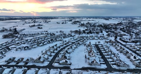Town covered in heavy winter snow. Aerial of homes in residential community at sunset. Aerial.