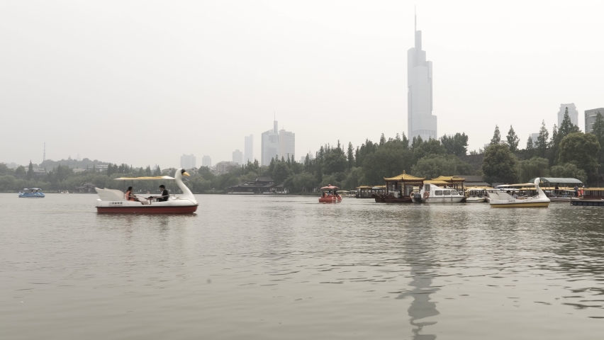 Busy boating lake in Nanjing, China, overlooked by the Zifeng tower and a polluted sky