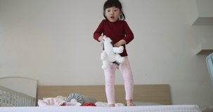 4K Video slow motion asian girl in red shirt jumping on the bed. Concept for happiness of kid and children.