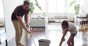 Teamwork makes the chores work. 4k video footage of a little girl mopping the floor with her father at home.