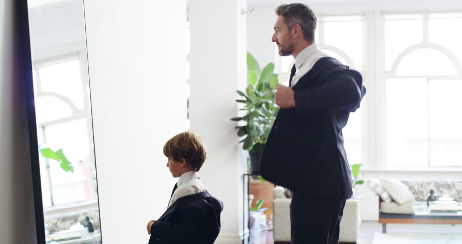 Mirror mirror on the wall, were the coolest of all. 4k video footage of an adorable little boy and his father getting dressed in matching suits at home.