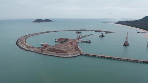 Hainan island, China - 02.05.2022: Land reclamation. Construction ships anchored at artificial island building site. Aerial shot.