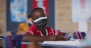 Animation of crayons over african american schoolboy wearing face masks. education, learning and development during covid 19 pandemic concept digitally generated video.