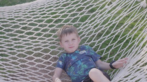 Funny smiling kid on hammock play outdoors