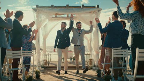 Handsome Gay Couple Walking Up the Aisle at Outdoors Wedding Ceremony Venue Near Ocean. Two Happy Men in Love Share Their Big Day with Diverse Multiethnic Friends. Authentic LGBTQ Relationship Goals. Video de stock