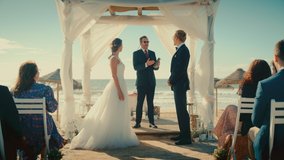 Beautiful Bride and Groom During an Outdoors Wedding Ceremony on a Beach Near the Ocean. Perfect Venue for Romantic Couple to Get Married, Kiss and for Friends with Multiethnic Cultures to Celebrate. - Powered by Shutterstock - Get 15% off with code: PIKWIZARD15