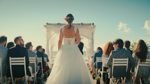 Beautiful Bride in Pure White Wedding Dress Going Down the Aisle, while Groom Waits at an Outdoors Ceremony Venue Near the Sea with Happy Multiethnic and Diverse Friends.