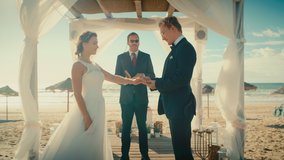 Beautiful Bride and Groom During an Outdoors Wedding Ceremony on an Ocean Beach. Perfect Venue for Romantic Couple to Get Married, Exchange Rings, Kiss and Share Celebrations with Multiethnic Friends. - Powered by Shutterstock - Get 15% off with code: PIKWIZARD15